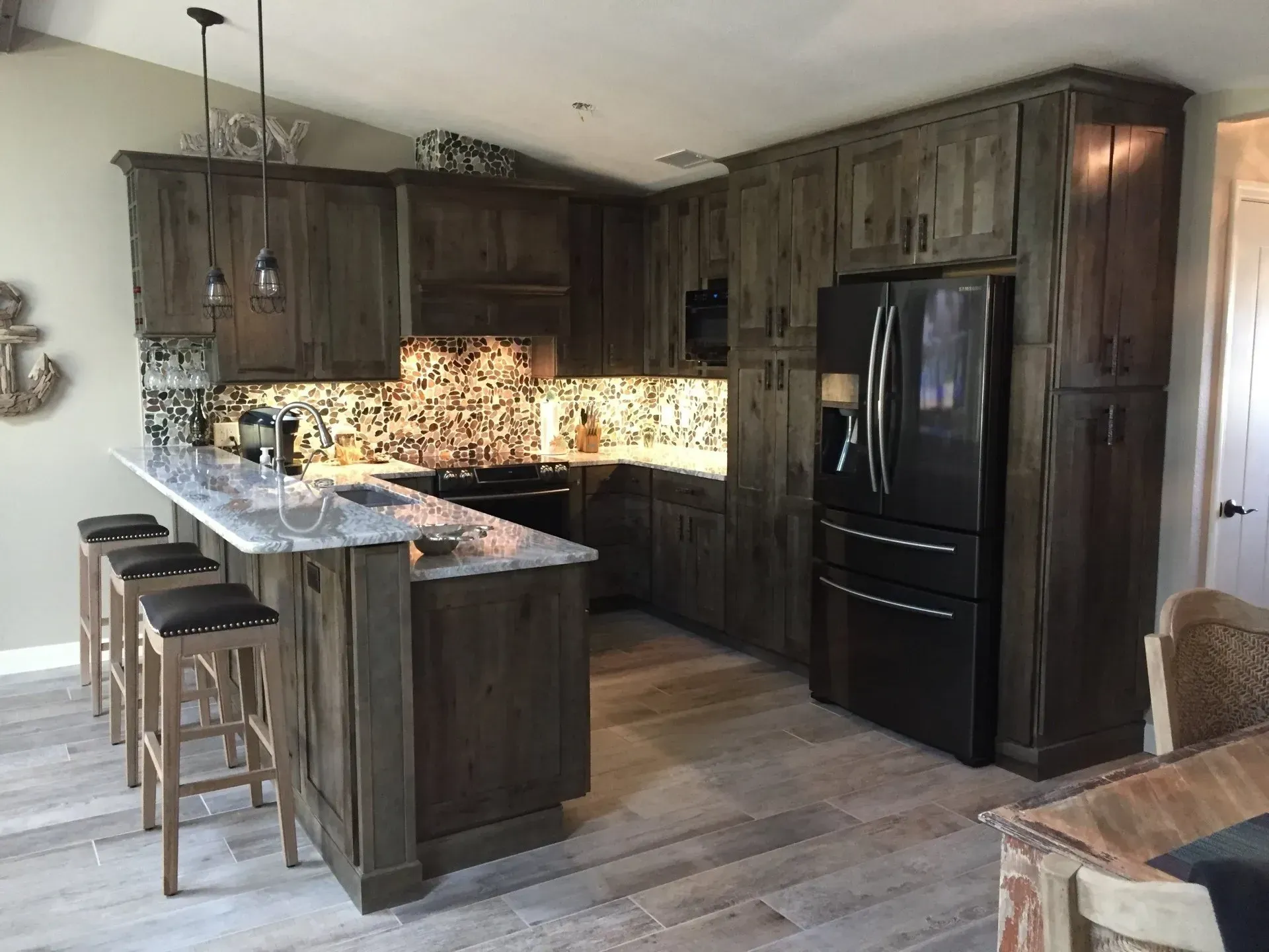 Rustic kitchen with dark wood cabinets, granite countertops, and a black refrigerator.