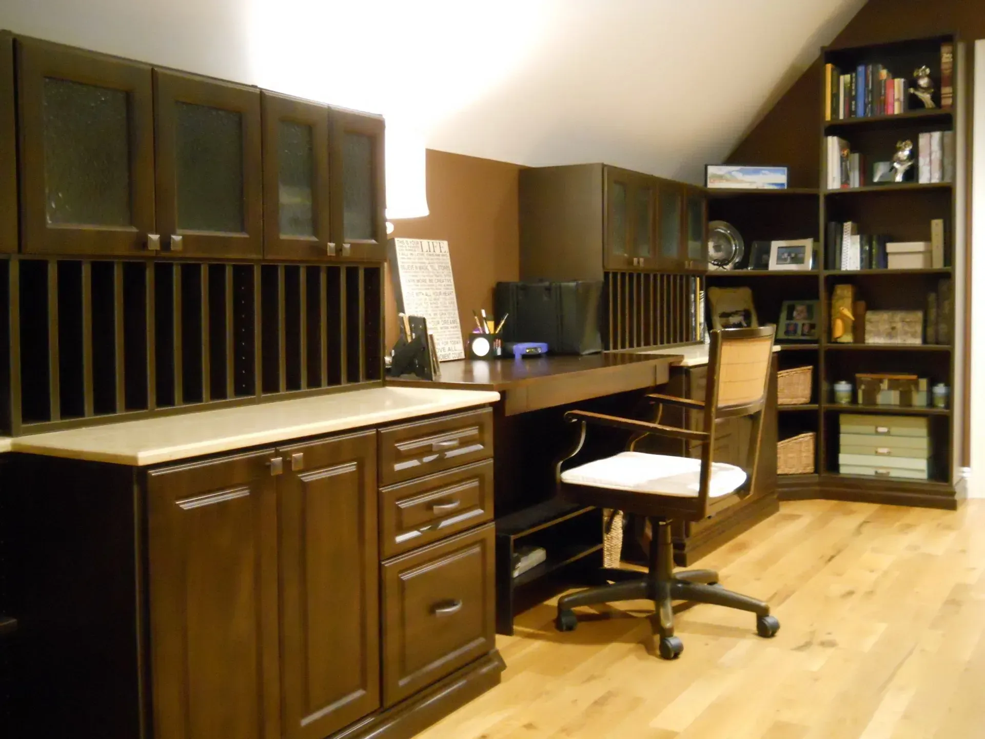 Dark wood home office with desk, cabinets, bookshelves, and hardwood floor.