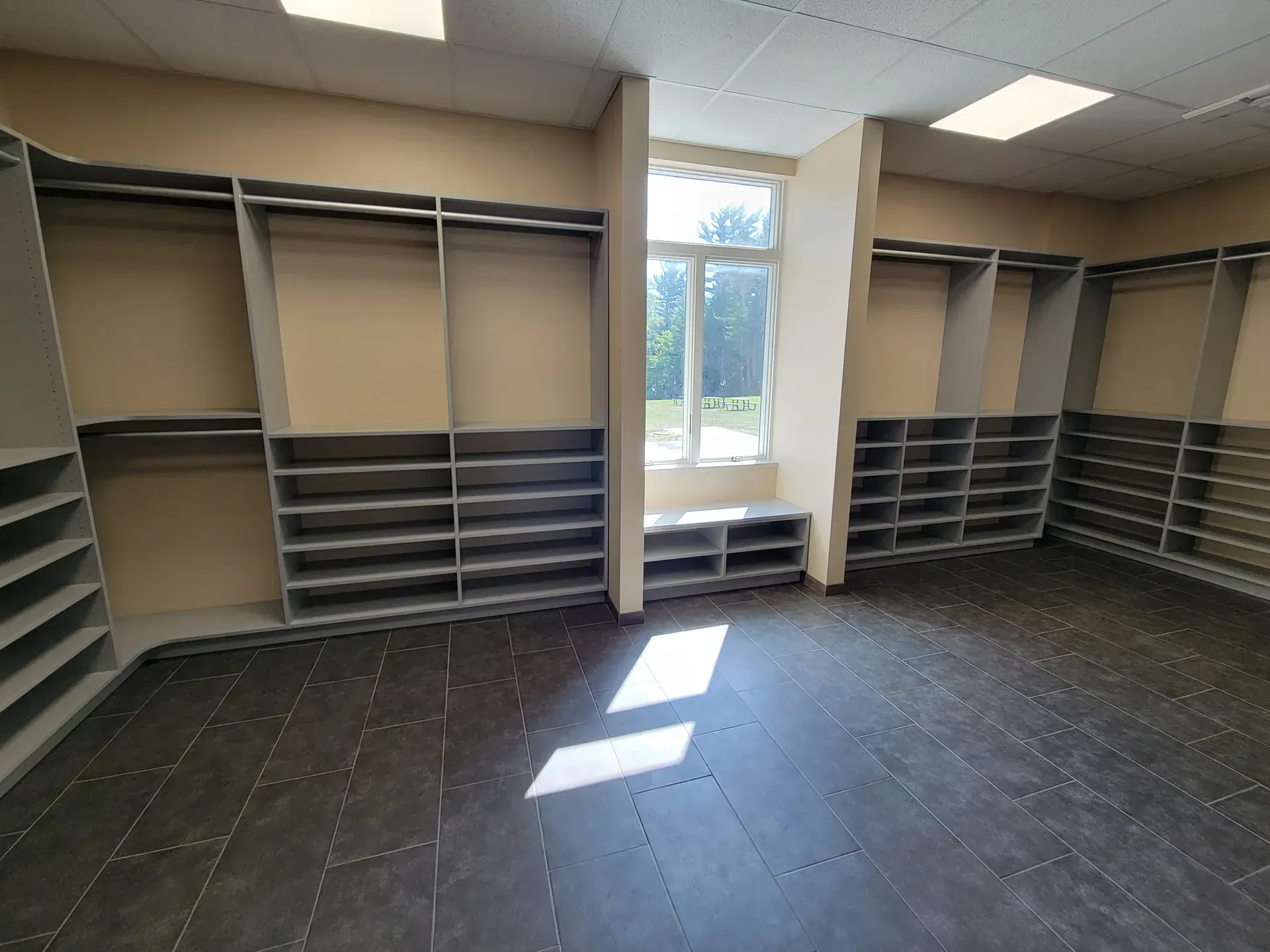 Empty walk-in closet with built-in shelves and racks, dark floor, and a window in the center.