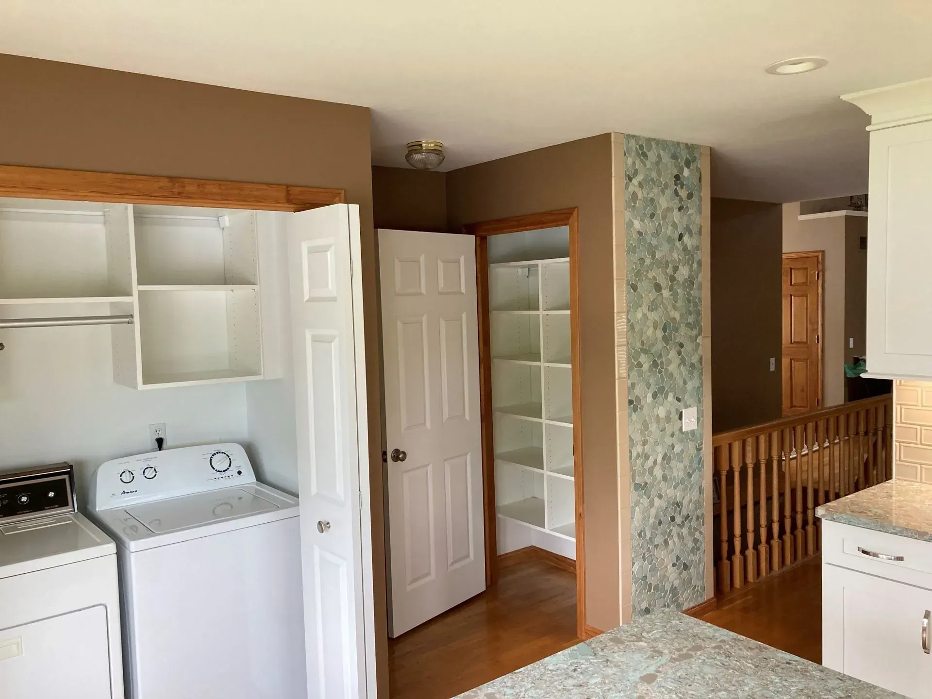 Laundry room with washer and dryer, pantry with shelves, and hallway with stairs.