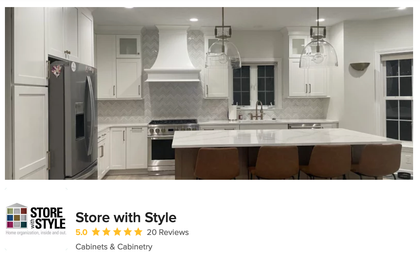 White kitchen with island and range, stainless steel appliances, light brown chairs, and glass pendant lights.