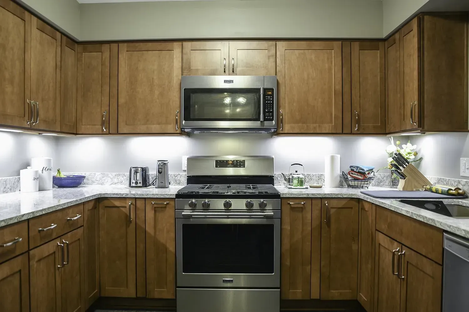Kitchen with brown cabinets, stainless steel appliances, and white countertops.