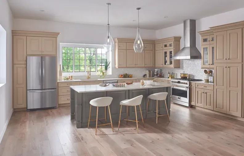 Spacious kitchen with light wood cabinets, island with bar stools, stainless steel appliances, and hardwood floors.
