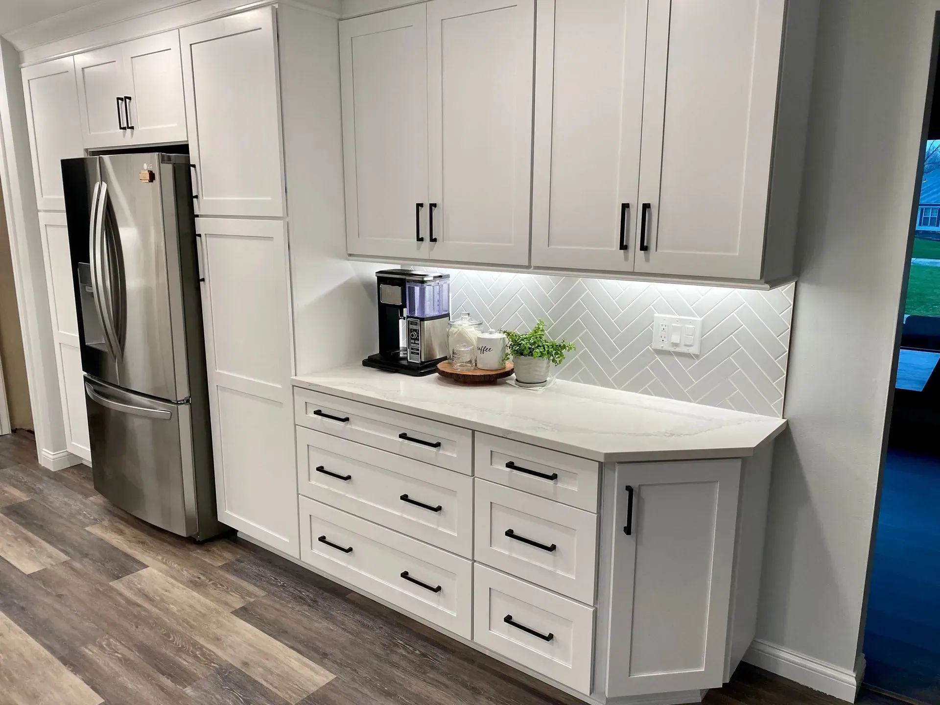 White kitchen cabinets with black hardware, a countertop, and appliances.