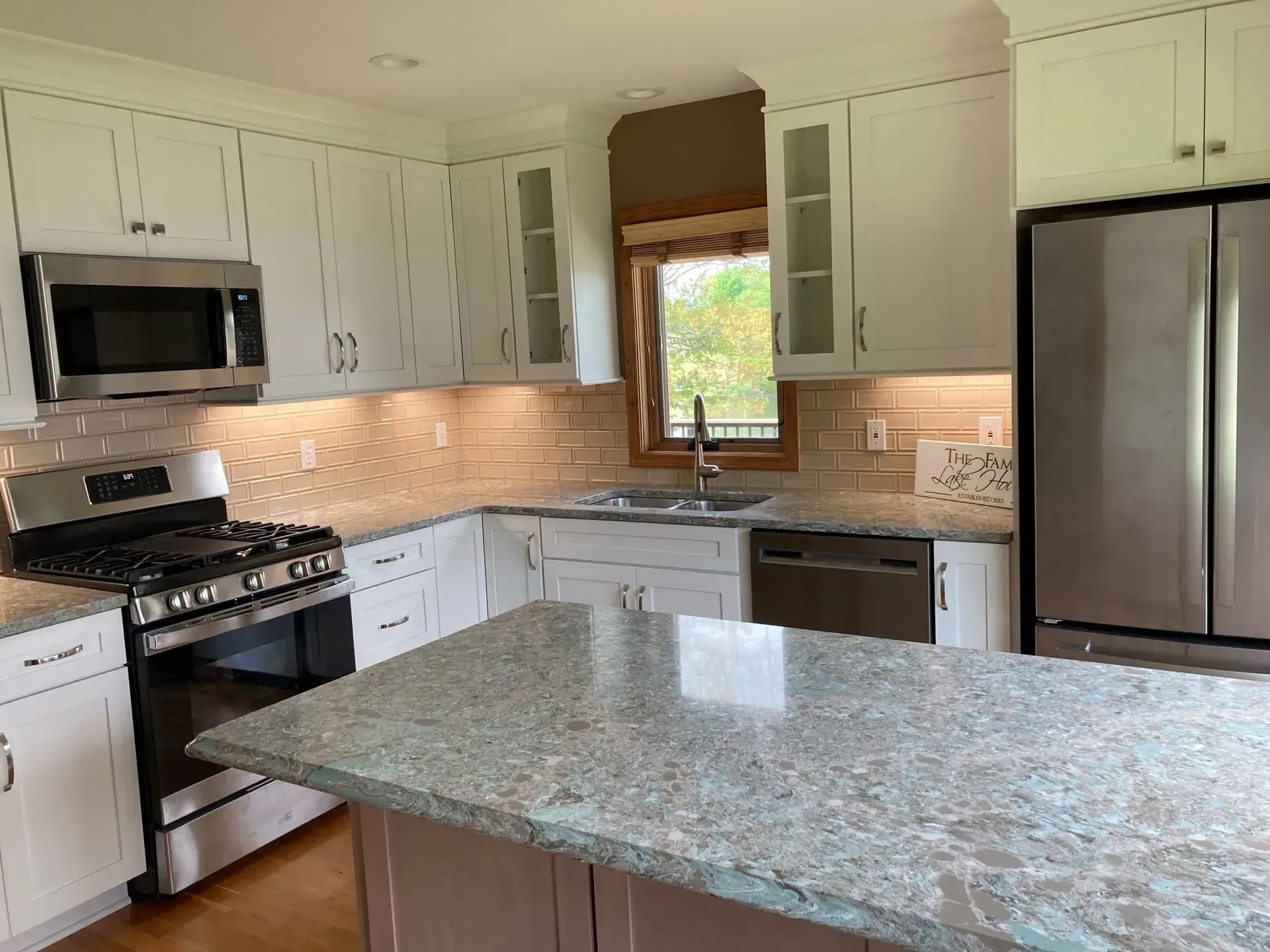 White kitchen with stainless steel appliances, granite countertops, and an island.