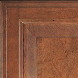 Close-up of a wooden cabinet door with a detailed, raised panel design and warm brown finish.