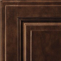 Close-up of a dark brown cabinet door with raised panel and intricate trim.