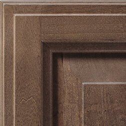 Close-up of a brown, wooden cabinet door detail, showing its carved frame and panel.