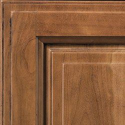 Close-up of a wooden cabinet door with a layered, recessed panel in a warm, brown stain.