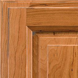 Close-up of a wooden cabinet door corner with warm, reddish-brown tones and layered detailing.