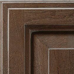 Close-up of a brown wood cabinet door with square panel and trim detail.