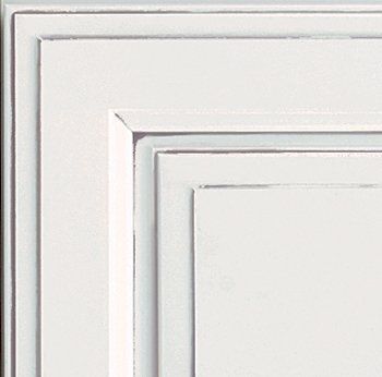Close-up of a white cabinet door, with layered square paneling and subtle distressing.