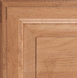 Close-up of a light brown wooden cabinet door with detailed paneling.