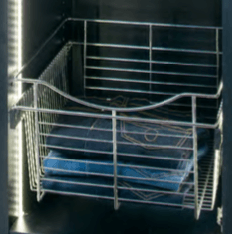 Metal wire basket holding folded blue jeans inside a dark closet.