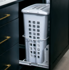 A pull-out laundry hamper inside a dark cabinet with gold handles.
