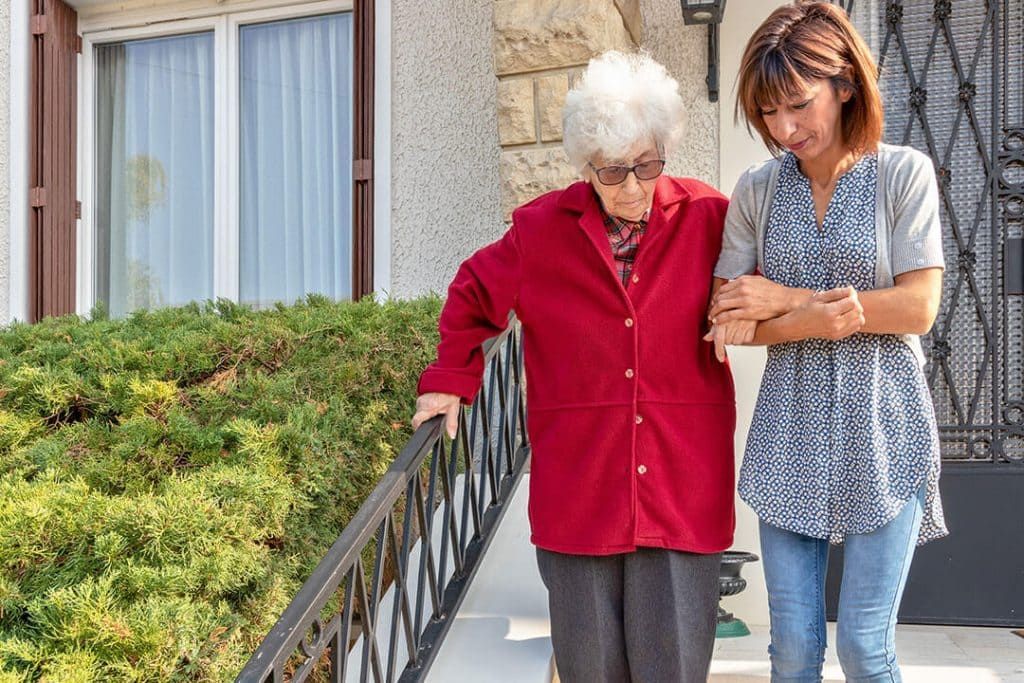 Une femme aide une femme plus âgée à descendre une rampe.