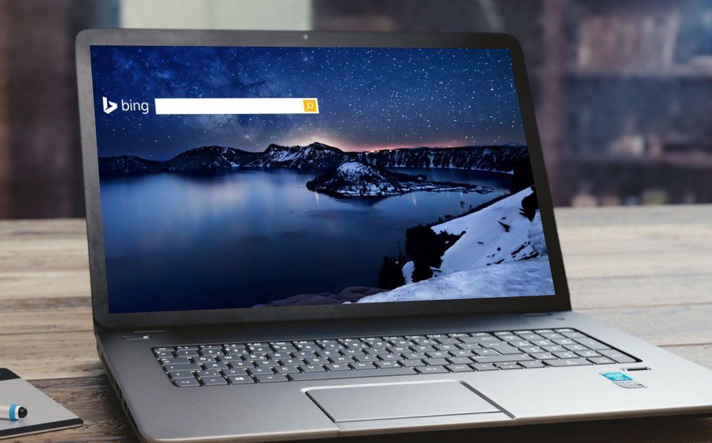 Laptop displaying Bing search page with a landscape of mountains and water.
