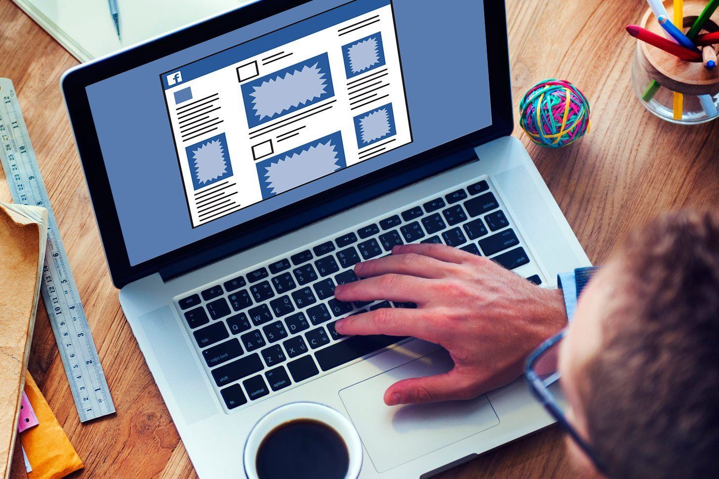 Person typing on laptop, website wireframe displayed on screen, coffee cup, desk supplies.