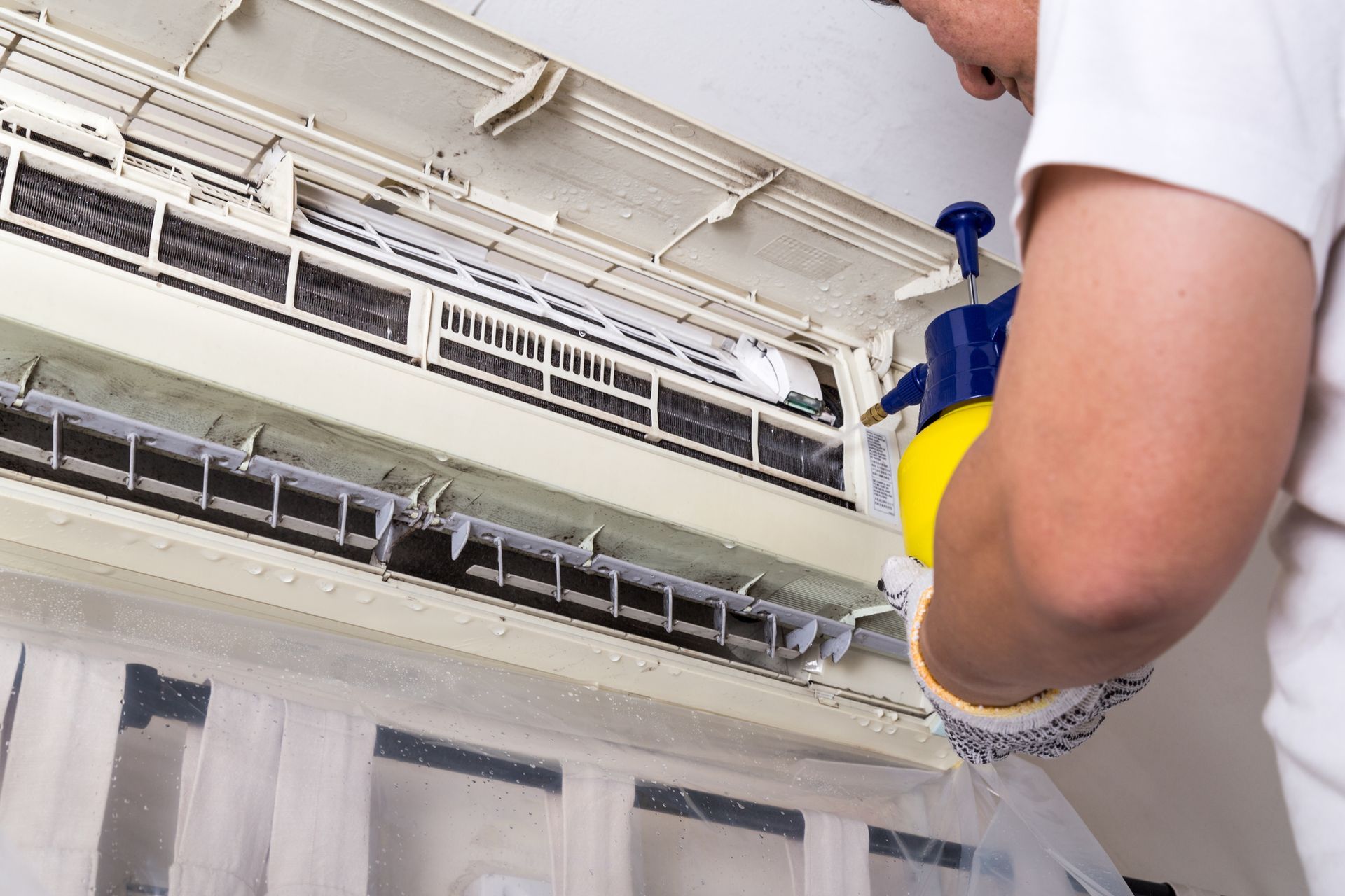 A person cleaning a air conditioner | Air Conditioning Services in Liverpool