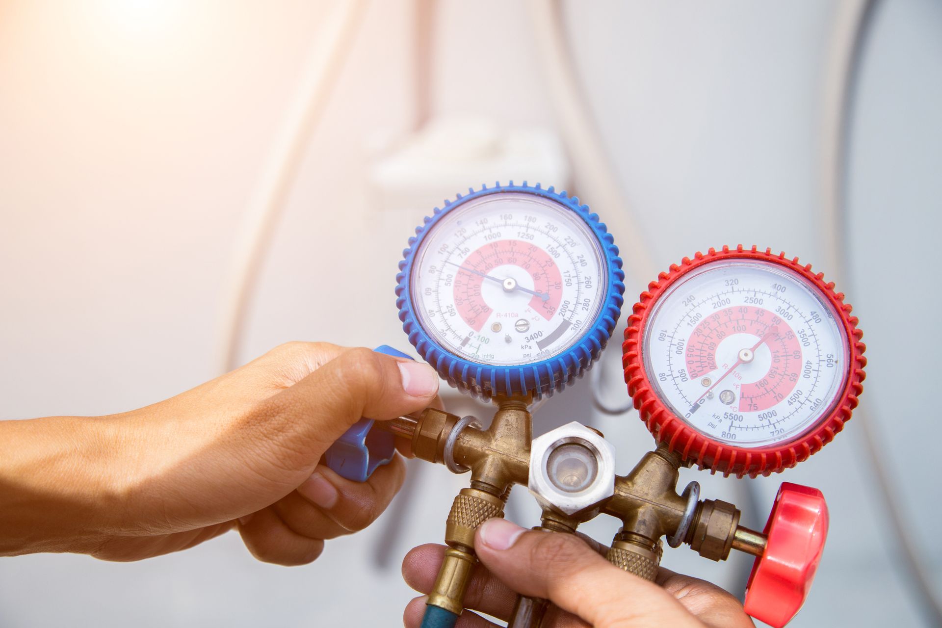 Close-up of an air con technician holding a pressure gauge and an air purifier.