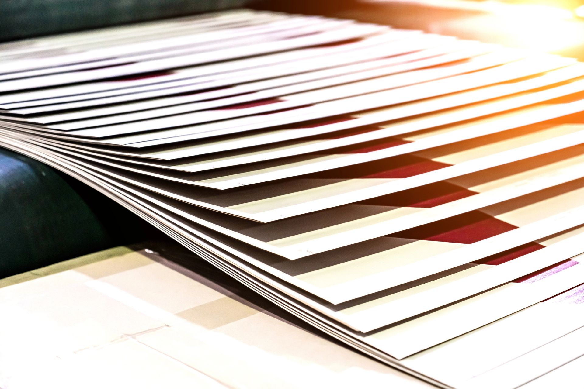 Pila di fogli stampati che escono da una macchina da stampa.