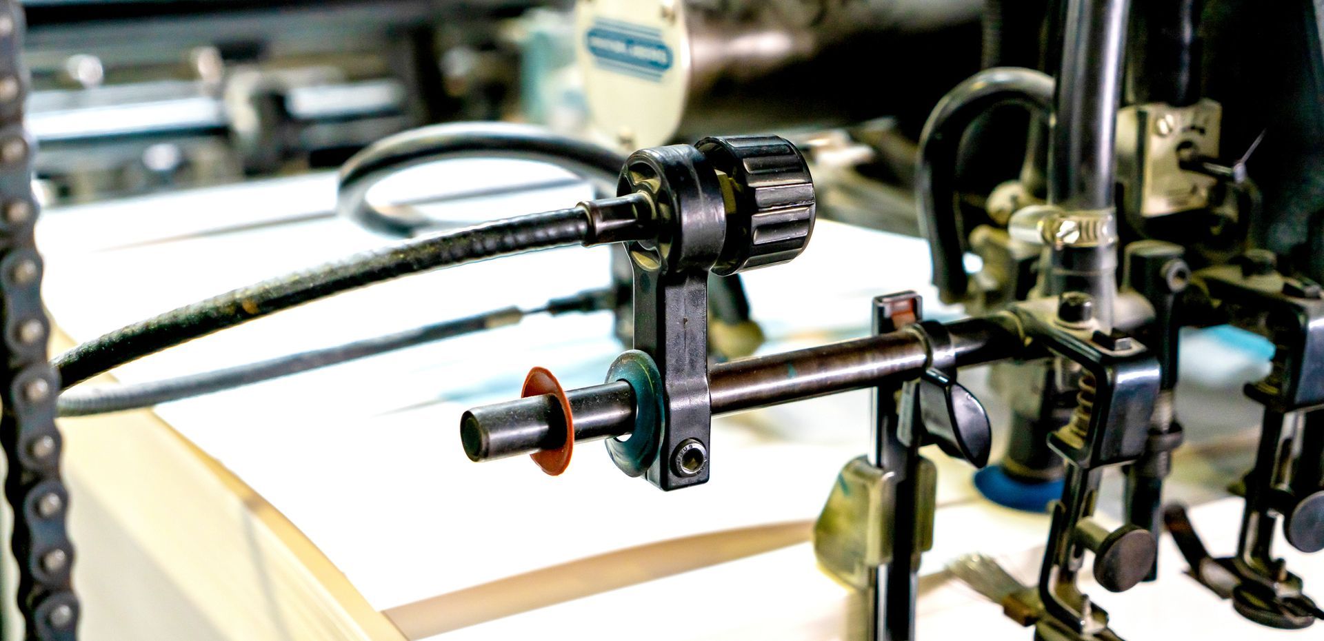 Primo piano di una macchina metallica con ingranaggi, un tubo nero flessibile e una catena, all'interno di un'officina.