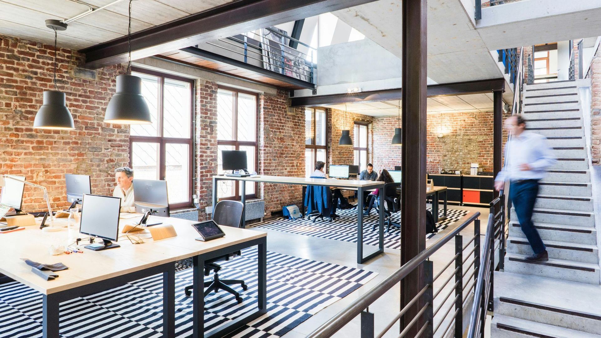 A man is walking down a set of stairs in an office.