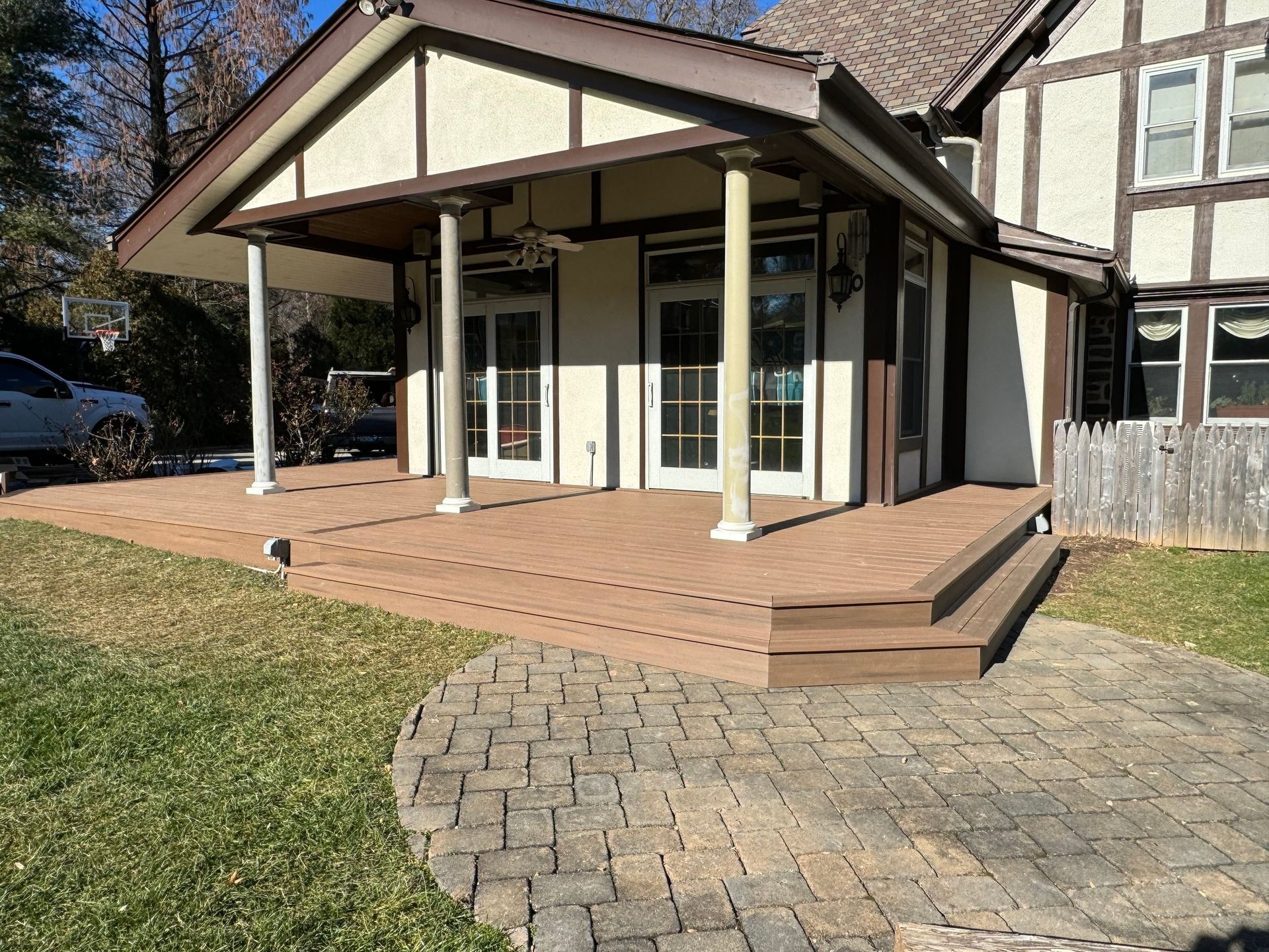 A house with a large deck and patio. Deck has brown composite planks. House has stucco and brown trim.