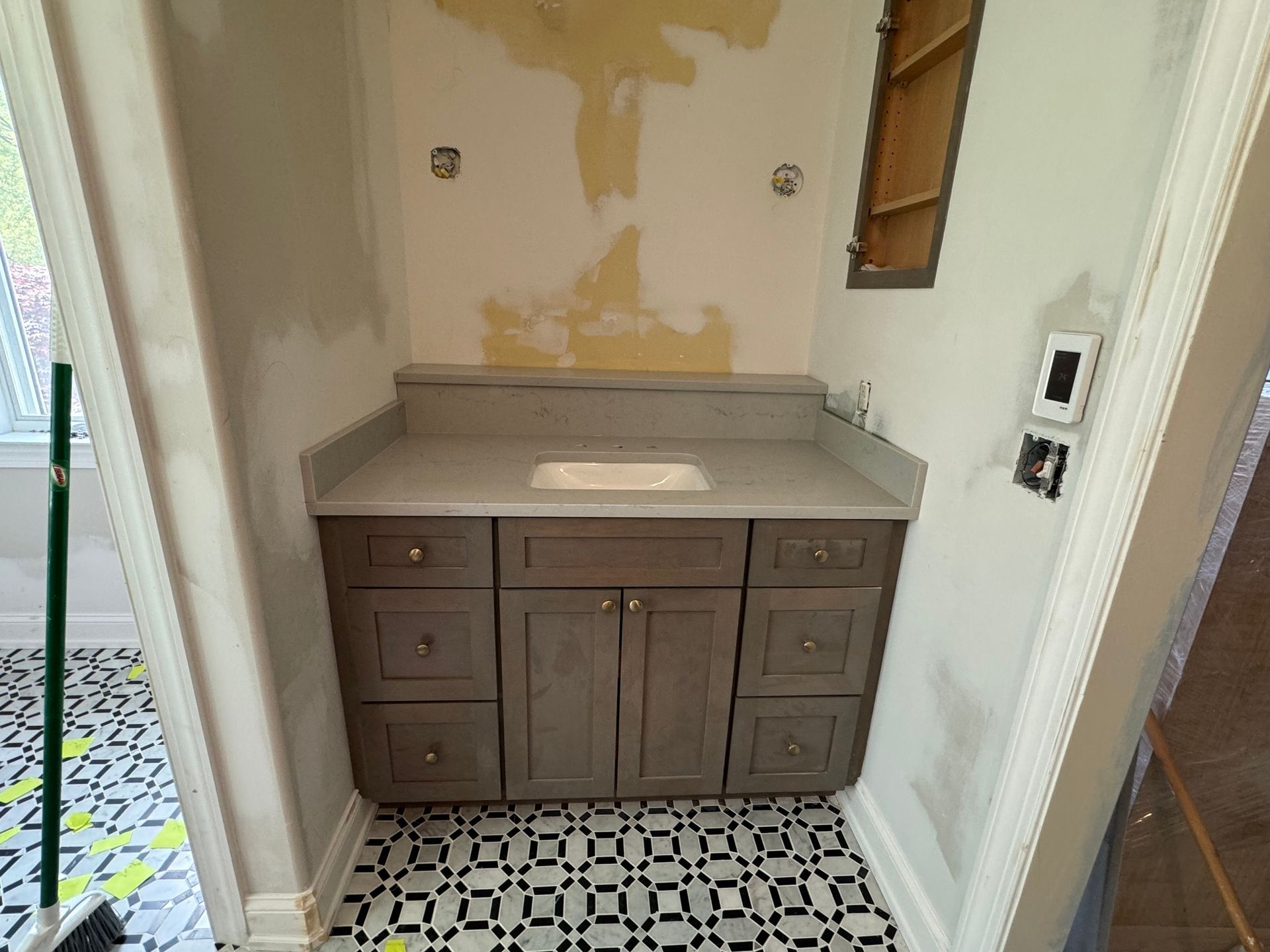 Bathroom with new gray vanity, countertop, and patterned tile floor. Walls are off-white.