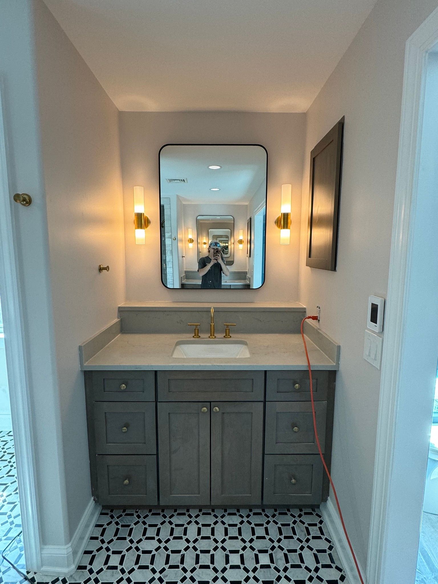 Small bathroom with a vanity, mirror, and patterned tile floor.