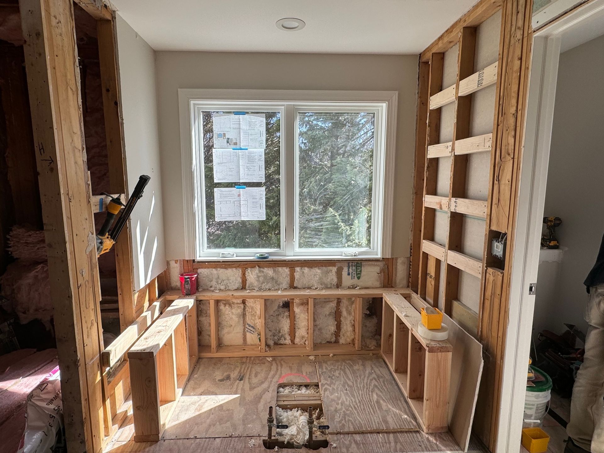 Bathroom under construction. Wooden frame surrounds a window and built-in bench. Insulation visible.