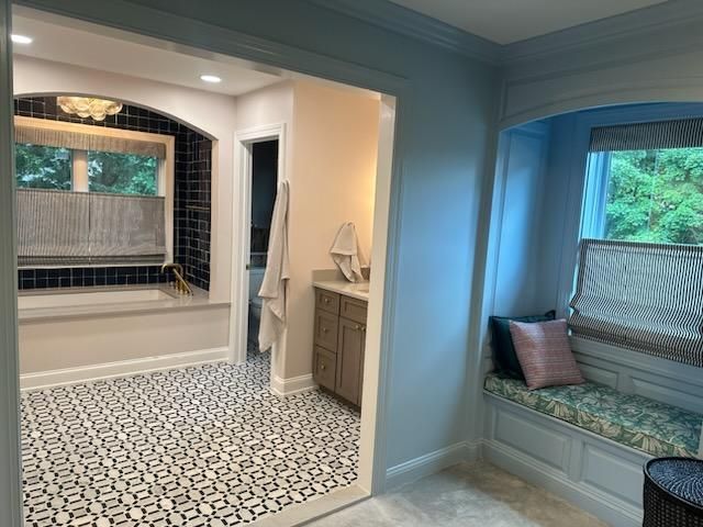 Bathroom with patterned floor, window seat, and an open doorway to a bathtub area.
