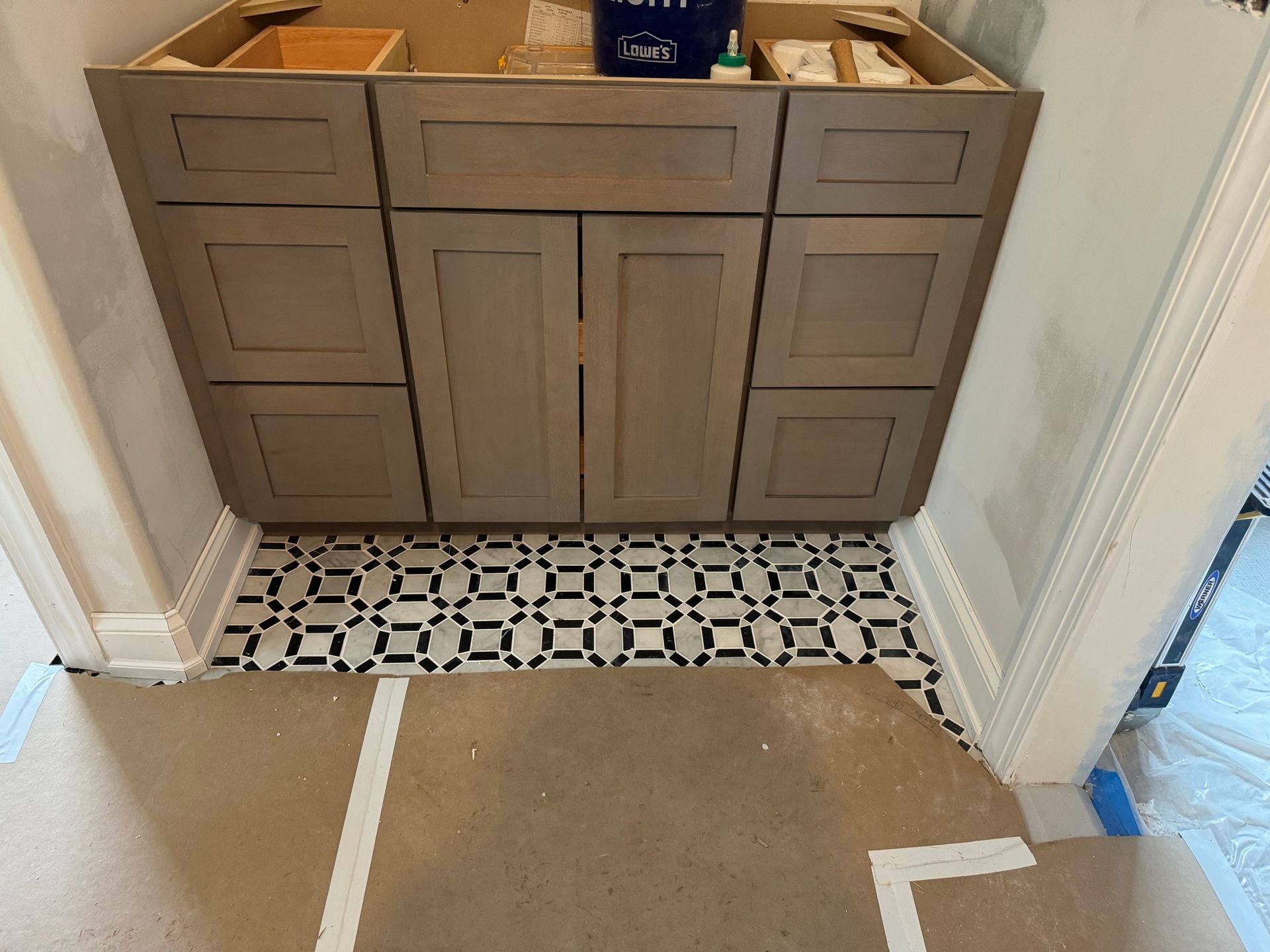 Bathroom vanity with gray cabinets over patterned tile floor; doorway edges visible.