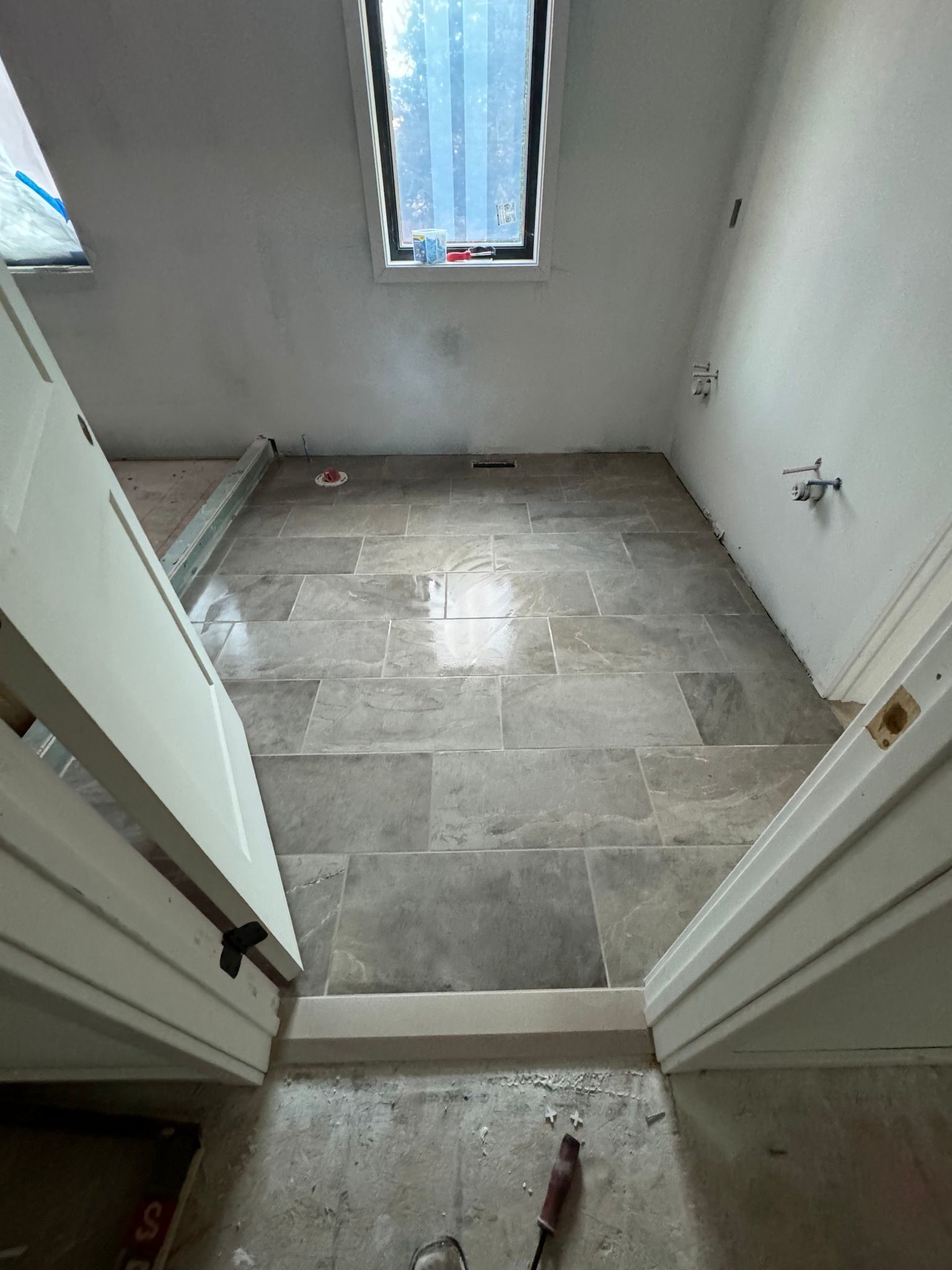 Bathroom with stone tile flooring, open white doors, and a skylight.