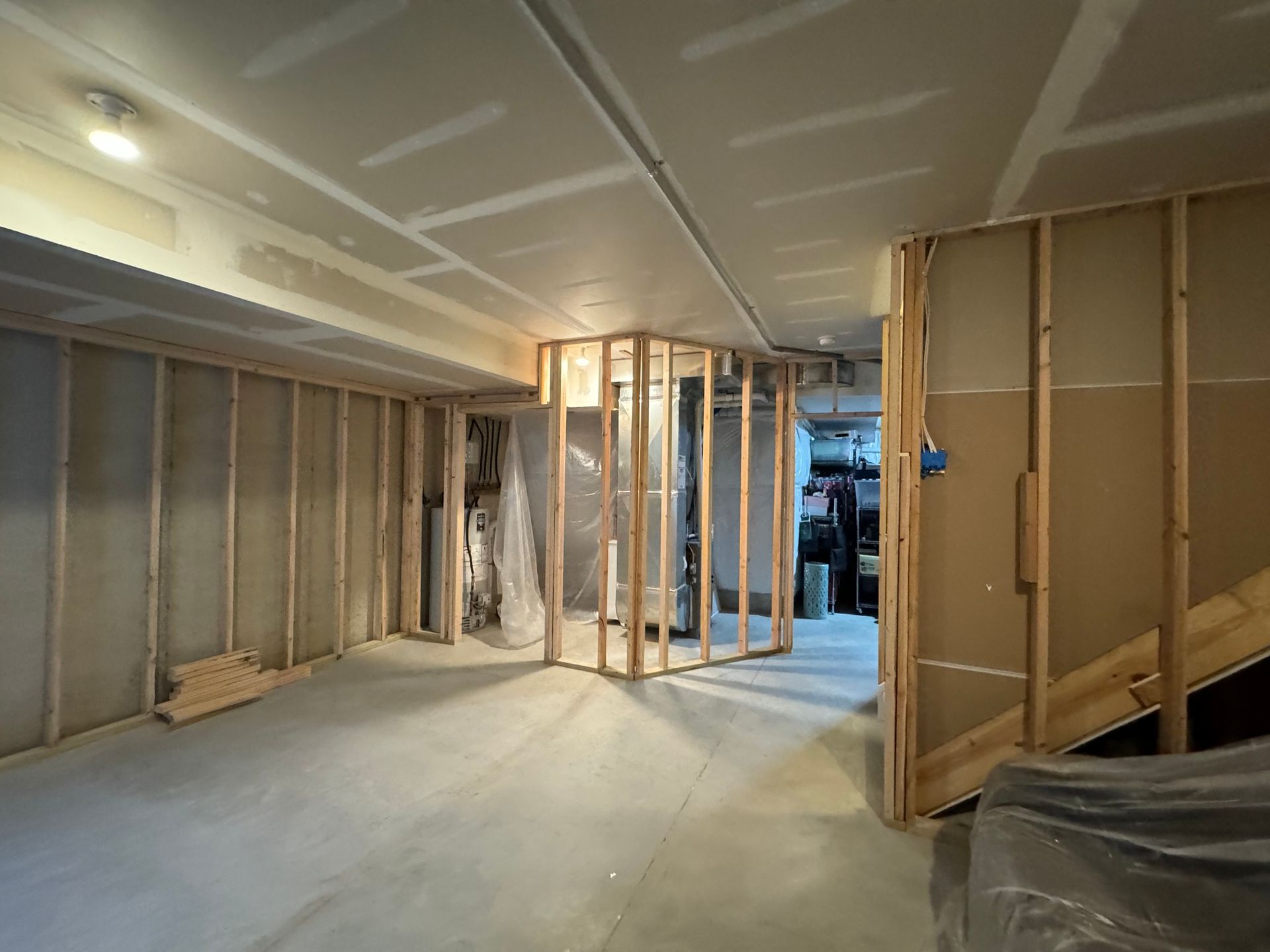 Interior of a basement under construction with exposed wooden framing and drywall.