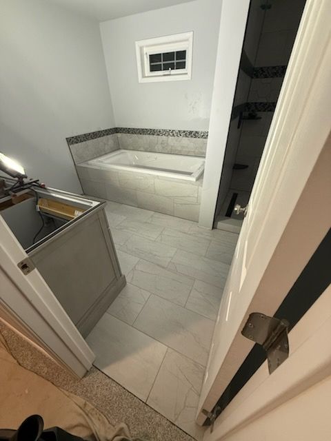 Bathroom renovation with a tiled floor, tub, and vanity, viewed from a doorway.