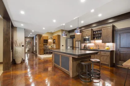 Rustic kitchen with a large island, stainless steel appliances, and dark wooden cabinets.