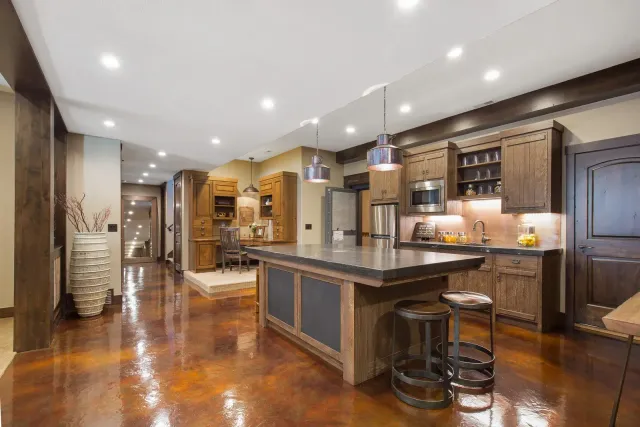 Rustic kitchen with a large island, stainless steel appliances, and dark wooden cabinets.