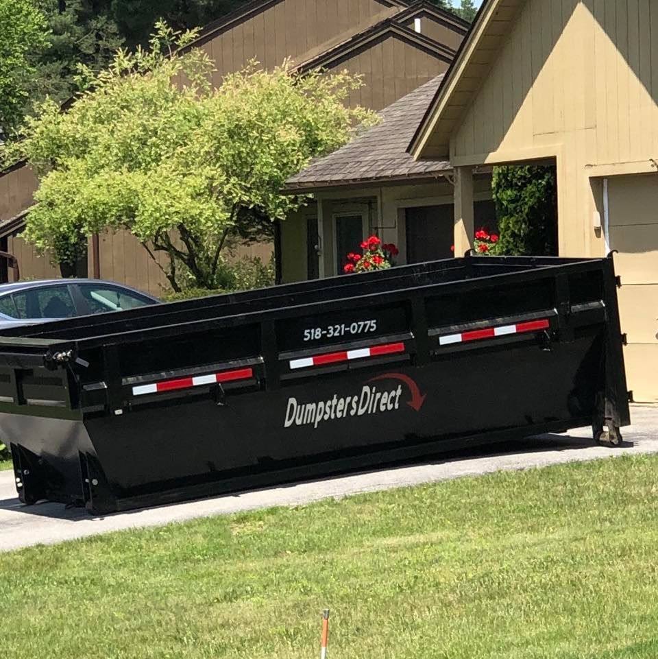 A dumpster is parked in front of a house.