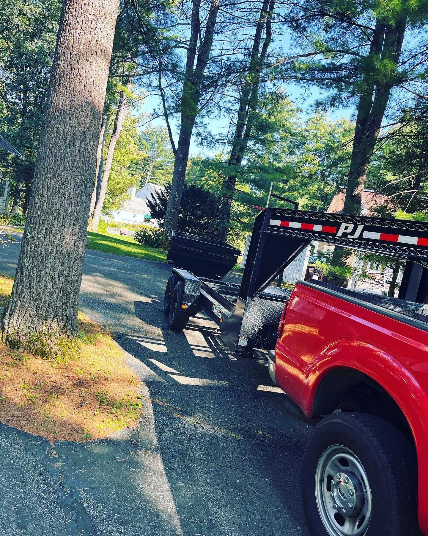 A red truck with a trailer attached to it is parked on the side of the road.