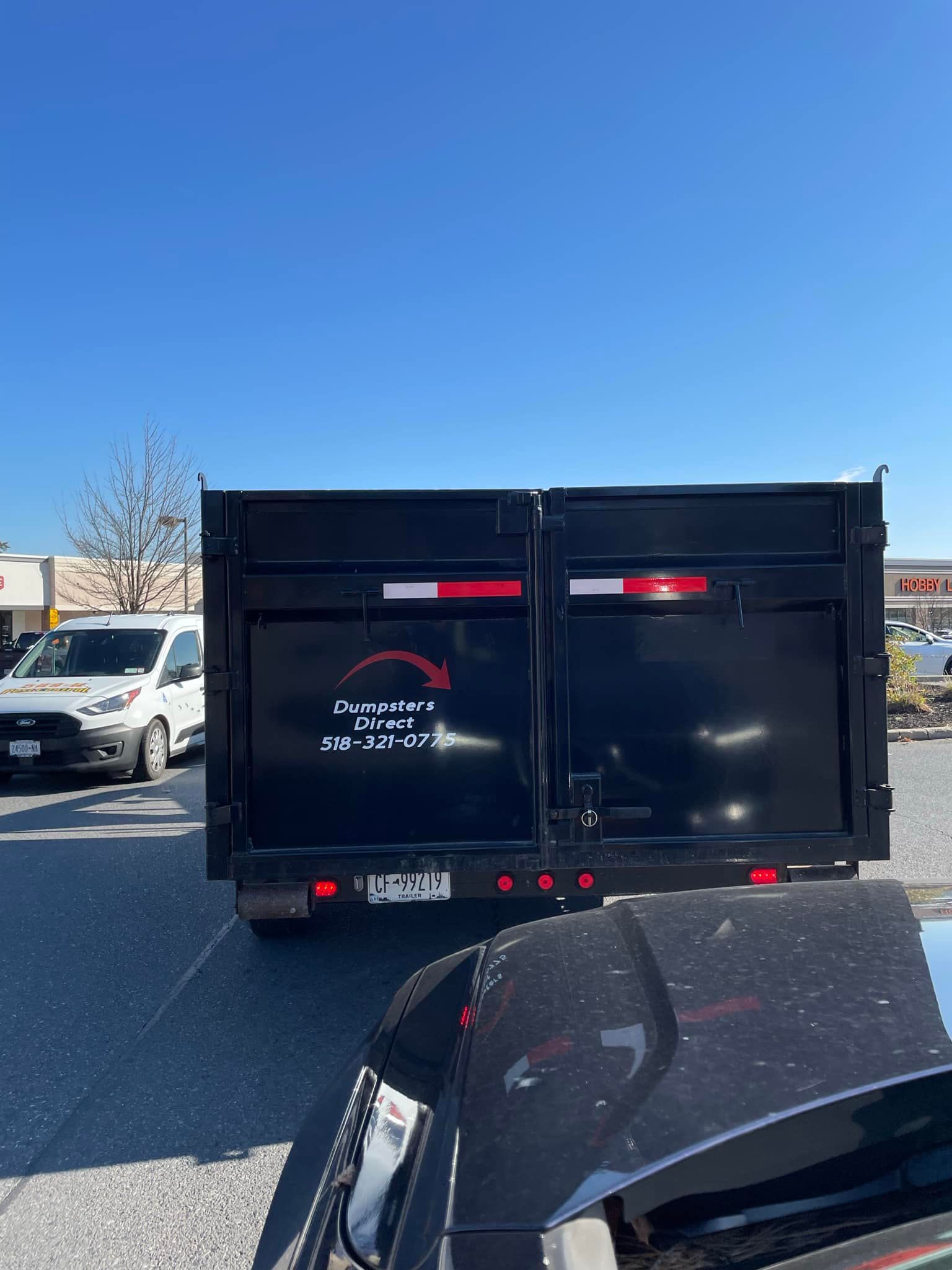 A dump truck is parked next to a car in a parking lot.