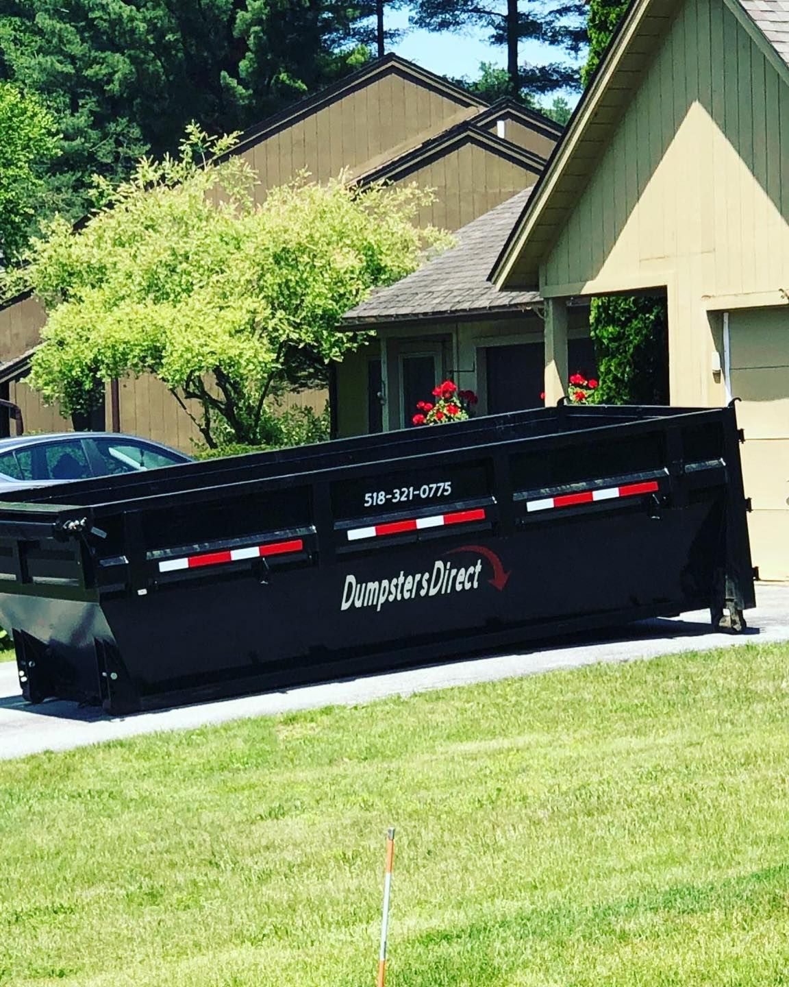 A dumpster is parked in front of a house.