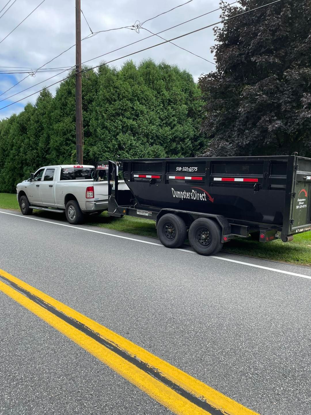 A dump truck and trailer are parked on the side of the road.