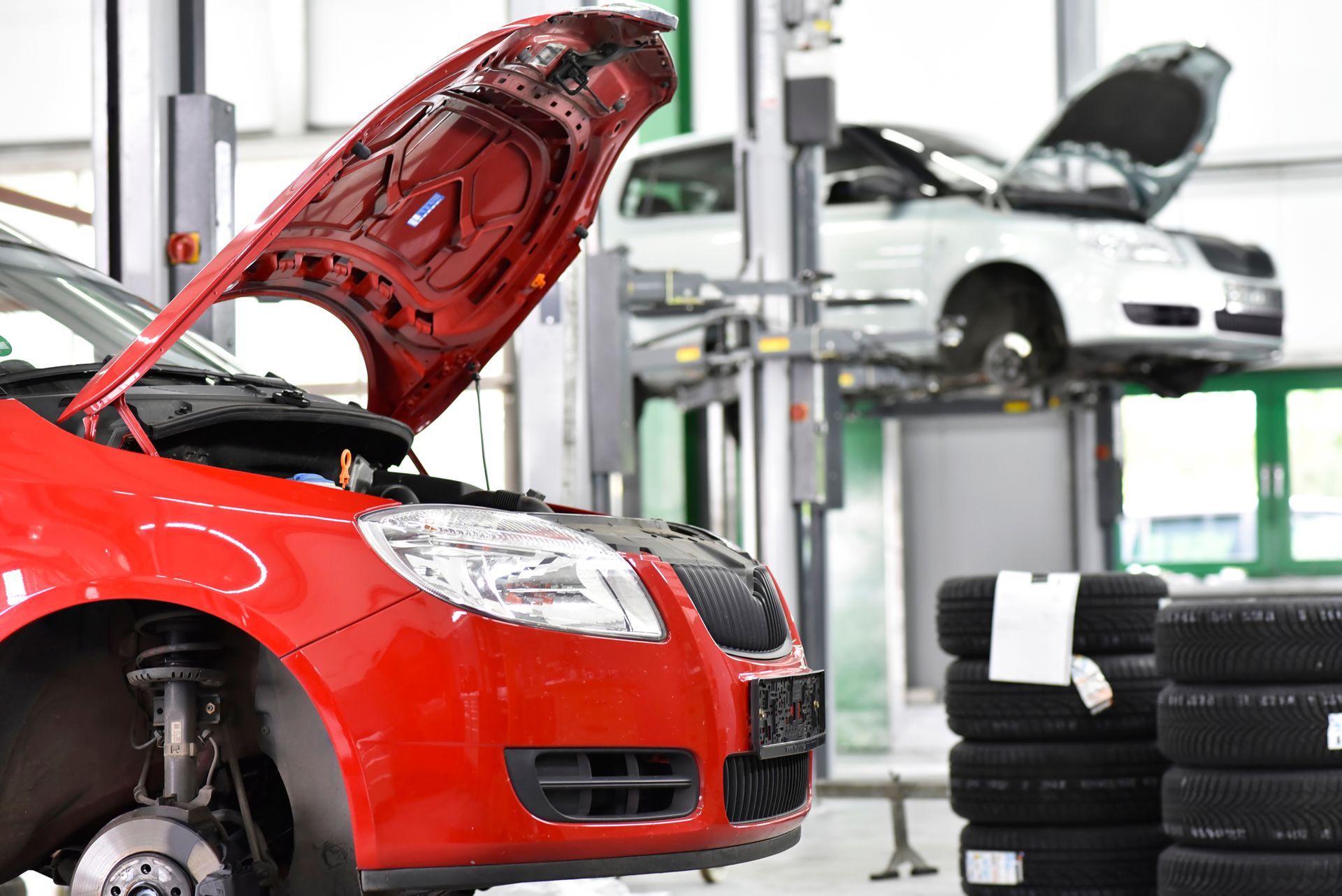 C'è una macchina rossa con il cofano alzato in un garage.