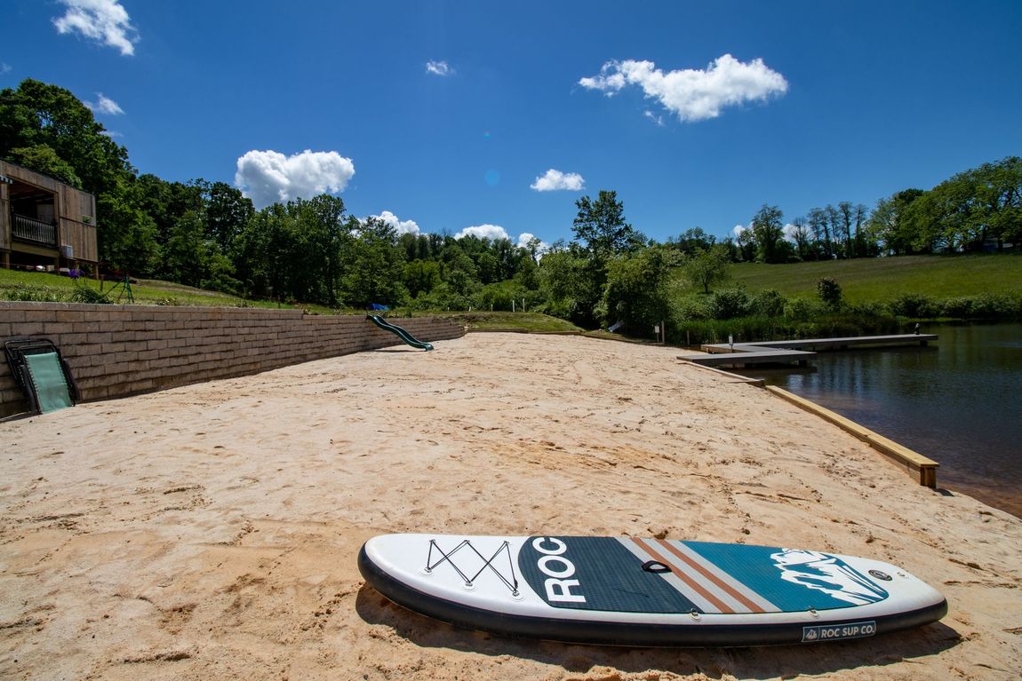 A surfboard is sitting on a sandy beach next to a body of water.