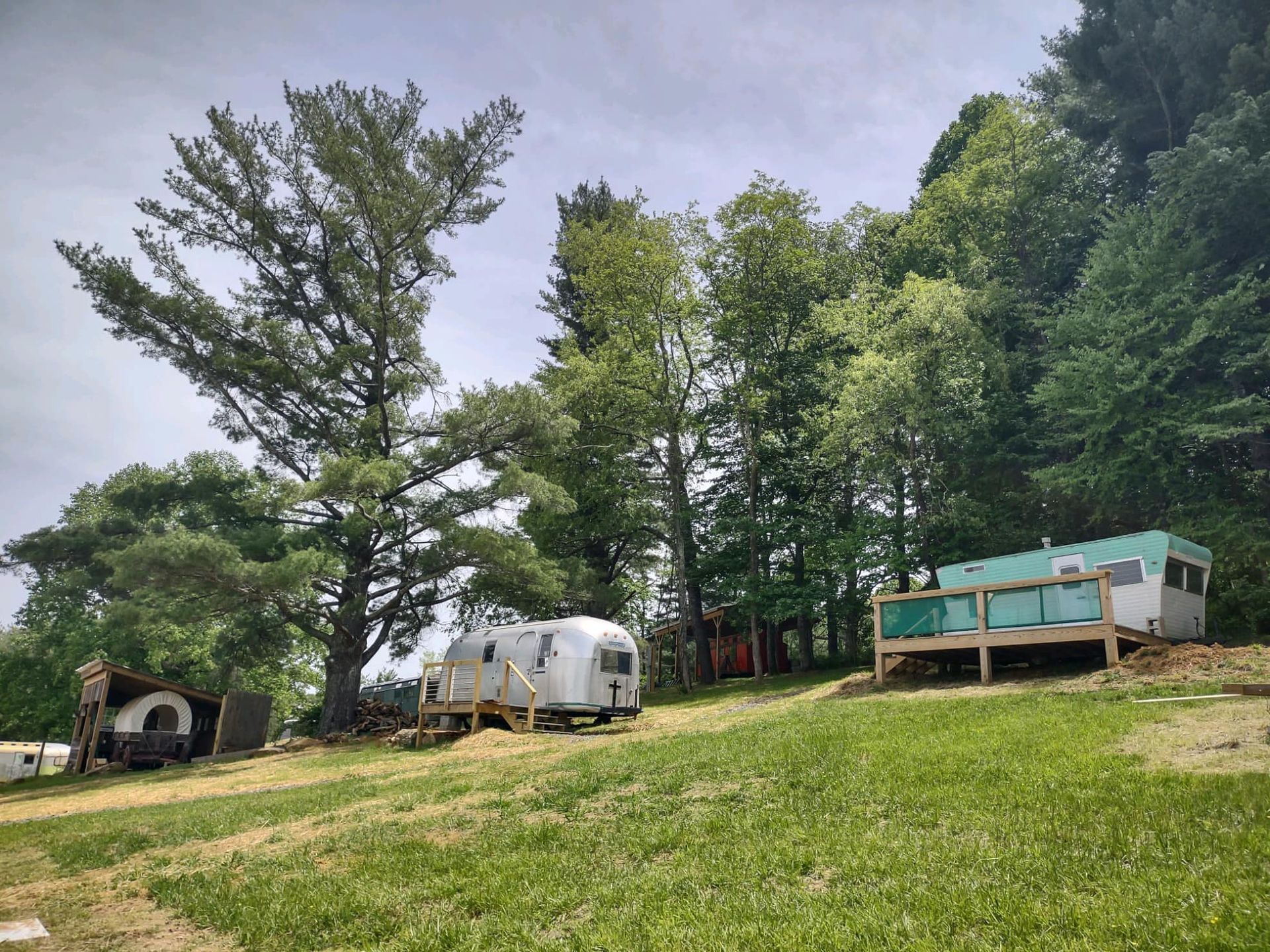 A rv is parked in a grassy field surrounded by trees.