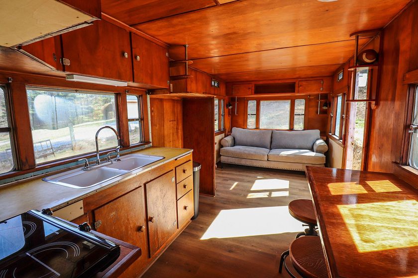 A kitchen with a sink , stove , couch and table.