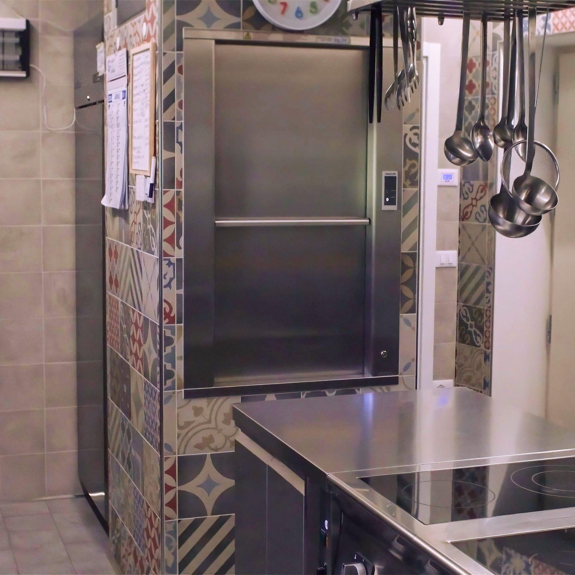 Montavivande da cucina, in acciaio inox, da incasso, rivestimento piastrellato, bancone in metallo, utensili da cucina sospesi.