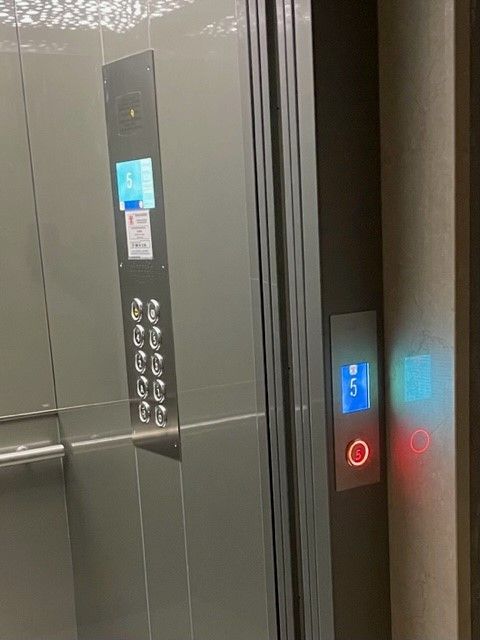 Interno dell'ascensore con pulsanti. Pannello metallico con pulsanti di piano e schermo. Pulsante illuminato sulla destra, che indica il piano 5.