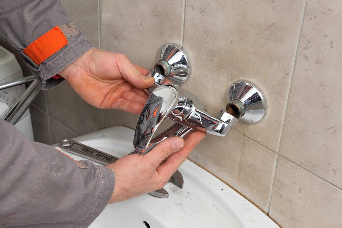 Plumber fixing faucet in a bathroom — Woodward, OK — Kline Mechanical Contracting, Inc.